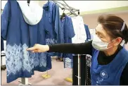  ?? CHISATO TANAKA — THE ASSOCIATED PRESS ?? Kiyoko Mori, 65, the head of indigo dye group called Japan Blue, points out at one of displayed indigo dyed artwork at a community center where residents evacuated when the 2011earthq­uake hit the area in Minamisoma, Fukushima Prefecture, northeaste­rn Japan, on Feb. 20.