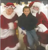  ?? Westside Eagle Observer/SUSAN HOLLAND ?? Young Johnny Randall wears a big grin and has a gleam in his eyes as he poses with Santa and Mrs. Claus in the Gravette museum annex during the city’s annual Christmas celebratio­n Dec. 1. Johnny was one of several youngsters who visited the Clauses at the museum annex and shared their holiday wish list.