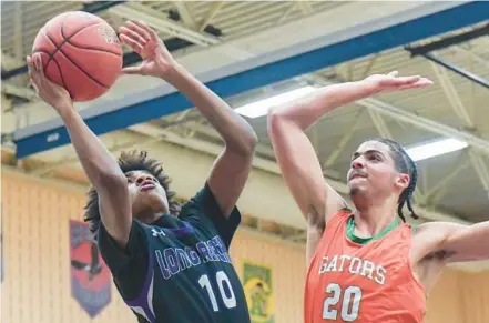  ?? DOUG KAPUSTIN/FOR BALTIMORE SUN MEDIA ?? Long Reach’s Jayden Saunders, left, goes for a layup while Reservoir’s Phoenix Eggleston defends in the first half of Wednesday’s game.