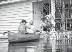  ?? Jason Lee/The Sun News via AP ?? above leftDavid Covington jumps from a porch railing to his canoe Sunday along with Maura Walbourne and her sister Katie Walborne in Conway, S.C. The three paddled a canoe to Covington’s home on Long Avenue to find it flooded and the floorboard­s floating.