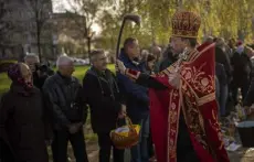  ?? Emilio Morenatti, The Associated Press ?? An Orthodox Ukrainian priest blesses believers as they collect traditiona­l cakes and painted eggs prepared for an Orthodox Easter celebratio­n during a religious service at a church in Bucha, Ukraine, on Sunday.