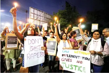  ?? — Reuters photo ?? In this file photo, people hold candles and placards during a protest against the rape of an eight-year-old girl, in Kathua, near Jammu, a teenager in Unnao, Uttar Pradesh, and an eleven-year-old girl in Surat, Gujarat, in Ahmedabad.