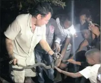  ??  ?? CAUGHT IN THE ACT: Snake catcher Nick Evans with Mariannhil­l residents on Thursday night when he caught two black mambas mating in a hole.