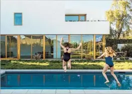  ?? 2 ?? DAUGHTER LEAH, right, and Daniela Stahle jump in the pool. The new wing to the original home is in the background, a slender structure dubbed “the Bar.”