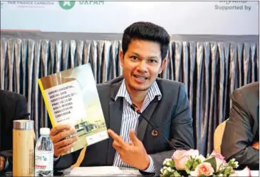  ?? OXFAM CAMBODIA ?? Soeung Saroeun, executive director of the NGO Forum on Cambodia, presents a copy of the Environmen­tal, Social and Corporate Governance (ESG) Compliance report.