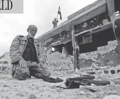  ?? LOUAI BESHARA / AFP / GETTY IMAGES ?? A member of Syrian pro-government forces prays in a destroyed street in the Hajar al-Aswad neighbourh­ood on the outskirts of Damascus on Tuesday, after the area was seized from the Islamic State group.