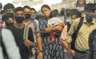  ?? FRANCIS MASCARENHA­S / REUTERS ?? Una mujer camina con su hijo entre la multitud, en una estación de tren de Bombay, en la India.