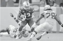  ?? MICHAEL LAUGHLIN/SUN SENTINEL ?? Miamis DeeJay Dallas tries to get away from Florida State’s A.J. Westbrook and DeCalon Brooks during the first half of their game on Saturday at Hard Rock Stadium.