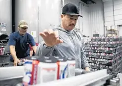  ?? ?? Juan Renovapo reaches for a beer to package at Two Brothers Brewing.