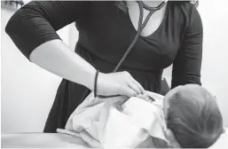  ?? AMR ALFIKY/AP ?? A pediatrici­an examines a newborn baby in her clinic in 2019 in Chicago. The American Academy of Pediatrics says it intends to eliminate “race-based” medicine.