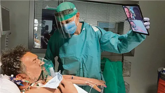  ?? FOTO ČTK/AP ?? Spojení s rodinou.
Doktor v nemocnici v italské Brescii drží tablet, aby se pacient na jednotce intenzivní péče mohl spojit s blízkými alespoň na dálku.