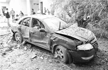  ?? — Reuters photo ?? A damaged car is seen during clashes between rival factions in Tripoli, Libya.