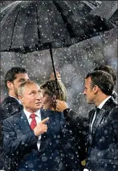  ??  ?? Under the weather: Putin and Macron share an umbrella on the podium
