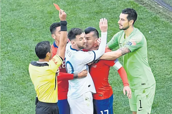  ??  ?? Paraguayan referee Mario Diaz de Vivar shows the red card to Argentina’s Lionel Messi and Chile’s Gary Medel during the Copa America.