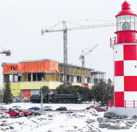  ?? ERROL MCGIHON ?? Cranes tower above the Museum of Science and Technology’s signature lighthouse and locomotive. The project, which is building storage space for the museum’s many items not on exhibit, is being scaled back due to cost.