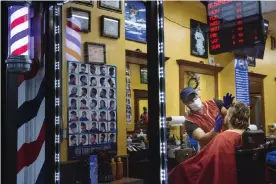  ??  ?? A barber wears a protective mask and gloves while cutting a customer’s hair at a shop in New Rochelle, New York. Photograph: Bloomberg/Bloomberg via Getty Images