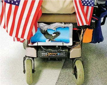  ?? [PHOTO BY JOHN CLANTON, TULSA WORLD FILE] ?? A veteran, whose wheelchair is decorated with flags and a license plate, rolls down the hallway in 2013 after a grounded honor flight in at the Oklahoma Department of Veterans Affairs Veterans Center in Claremore.
