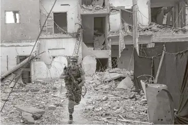  ?? Hussein Malla / Associated Press ?? A U.S.-backed Syrian Democratic Forces fighter races away from a damaged building as he crosses a street on the front line Thursday in Raqqa city, northeast Syria.