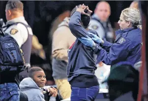  ?? CP PHOTO ?? A Royal Canadian Mounted Police officer frisks a woman as she is processed before being turned over to the Canada Border Services Agency at a tent in Saint-Bernard-de-Lacolle, Que.