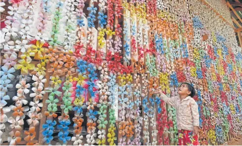  ?? AFP ?? A boy looks at a decoration made of recycled plastic water bottles at the Coconut School in Kampong Speu province early this month.