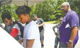  ??  ?? Omarion Inniss, 15, and Jashon Gulledge, 14, help Herbert “Book” McCray sort shirts at Booker T. Washington State Park. Both have been in McCray's program for five years.