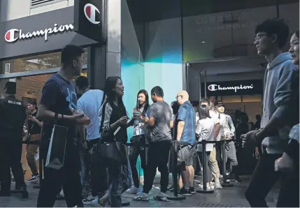  ?? Andy Wong, The Associated Press ?? People walk by shoppers in line to enter a sportswear store for American brand Champion at Beijing’s popular shopping mall on Monday. China raised tariffs Monday on thousands of U.S. goods in an escalation of its fight with President Donald Trump over technology policy and accused Washington of bullying Beijing and damaging the global economy.