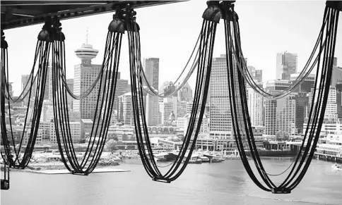  ??  ?? Downtown Vancouver is pictured through a crane’s wires at the Port of Vancouver terminal in Vancouver, British Columbia, Canada, on Thursday, July 21, 2016. — WP-Bloomberg photo