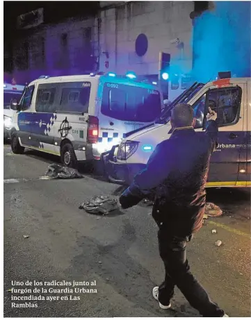  ??  ?? Uno de los radicales junto al furgón de la Guardia Urbana incendiada ayer en Las Ramblas