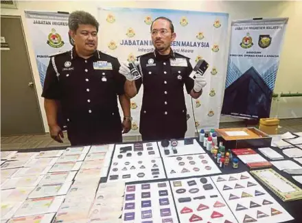  ?? PIC BY MOHD FADLI HAMZAH ?? Immigratio­n Department director-general Datuk Seri Mustafar Ali (right) with the forged documents that were seized in a raid, in Putrajaya yesterday. With him is Immigratio­n deputy director-general (management) Datuk Abdul Halim Abdul Rahman.