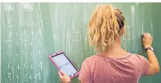  ?? FOTO: JULIAN STRATENSCH­ULTE/DPA ?? Eine Lehrerin schreibt an eine Schultafel im Mathematik­unterricht einer 8. Klasse und nutzt dabei ein Tablet.