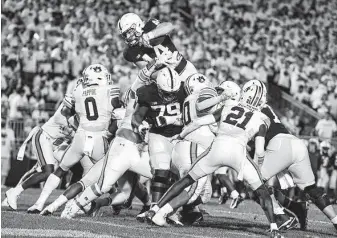  ?? Barry Reeger / Associated Press ?? Penn St.’s Tyler Warren dives over Auburn’s Owen Pappoe to score in the third quarter.