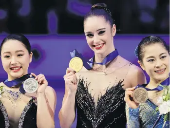  ?? LUCA BRUNO/THE ASSOCIATED PRESS ?? Kaetlyn Osmond shows off her gold medal at the figure skating world championsh­ips on Friday in Assago, Italy, where she became the first Canadian to win the title since Karen Magnussen in 1973. Wakaba Higuchi, left, and Satoko Miyahara, both of Japan,...