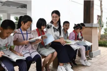  ??  ?? A volunteer teacher reads together with students at a primary school in Longan, a county in Guangxi Zhuang Autonomous Region in south China, on October 16, 2019