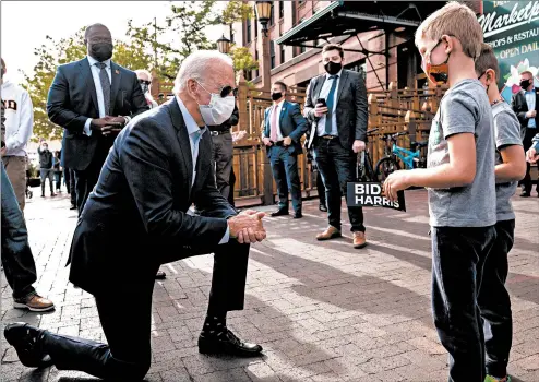  ?? ERIN SCHAFF/THE NEW YORK TIMES ?? Joe Biden, the Democratic presidenti­al nominee, stops to chat with two boys while campaignin­g in Duluth, Minnesota.
