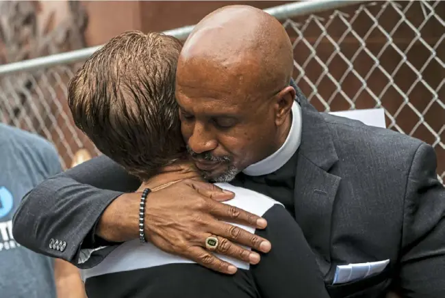  ?? Michael M. Santiago/Post-Gazette ?? Andrea Wedner, of Squirrel Hill, left, is embraced by Pastor Eric Manning, of Emanuel AME Church, on May 3 after a prayer service with survivors of the mass shootings at the South Carolina church in 2015 and Tree of Life synagogue. The service was held at Tree of Life in Squirrel Hill.