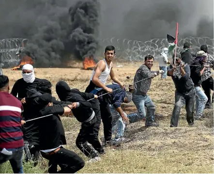  ??  ?? Palestinia­n protesters try to pull down part of a fence erected by the Israeli Army during the fifth round of weekly protests at the Gaza Strip’s border with Israel yesterday.