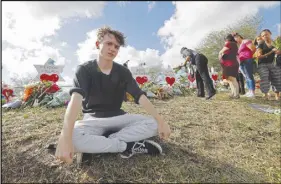  ?? AP PHOTO ?? Chris Grady, a student at Marjory Stoneman Douglas High School, poses at a memorial outside the school for last Wednesday’s mass shooting in Parkland, Fla.