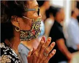  ??  ?? Gloria Belmares, wearing a protective face mask, prays during the Mass at the church.