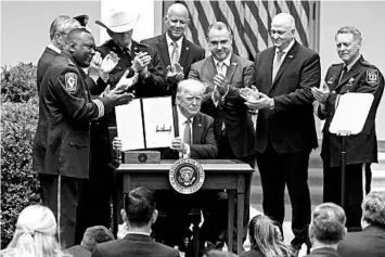  ?? DOUG MILLS/THE NEW YORK TIMES ?? President Donald Trump, surrounded by law enforcemen­t officials, shows an executive order on policing changes Tuesday.