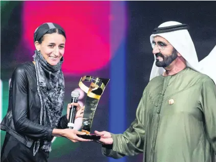  ?? Reem Mohammed / The National ?? Sheikh Mohammed bin Rashid, Vice President and Ruler of Dubai, presents Nawal Al Soufi with her prize, for work with refugees trying to cross the Mediterran­ean Sea, at the Arab Hope Makers awards ceremony at Dubai Studio City.