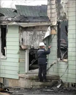  ??  ?? Investigat­or Debbie Harris of the Ontario Fire Marshal’s Office takes photos at the scene of an early morning fire on Sunday in Waterloo.