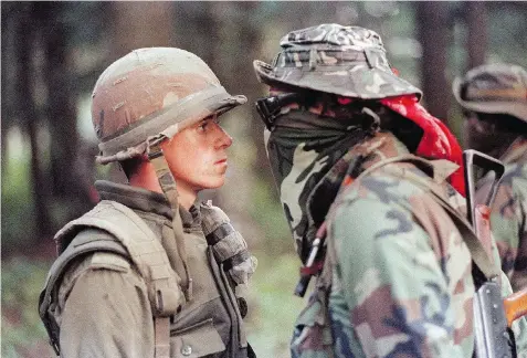  ?? SHANEY KOMULAINEN/The Canadian Press files ?? Canadian soldier Patrick Cloutier and Saskatchew­an First Nations members Brad Laroque, alias ‘Freddy Kruger,’
come face to face in a tense standoff at the Kanesatake reserve in Oka, Que., on Sept. 1, 1990.