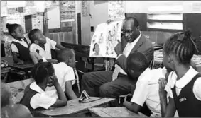  ??  ?? Education, Youth and Informatio­n Minister, Senator the Hon. Ruel Reid, points out features of the book, ‘Big and Strong’ to a group of students of the Chetolah Park Primary School in West Kingston.