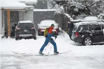  ??  ?? URBAN SKIER: A man uses skis to make his way down the road Saturday in Seattle after a storm hit the city with rare heavy snowfall.