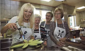  ??  ?? Feurig-fröhliches Grillen: Susanne Stangl flämmt die Gurke mit dem Bunsenbren­ner für die Röstaromen. Gudrun Hoppe, Jutta Cosalter und Elisabeth Hakvoort schauen zu.