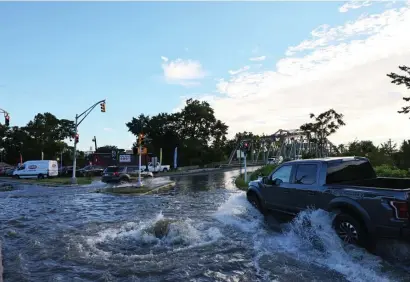  ?? Getty IMages ?? RECORD RAIN: A pickup drives through a flooded street as water gushes out of a manhole last week in Passaic, N.J. Two friends were still missing Sunday night in Passaic after floodwater­s picked up their car and carried it away.