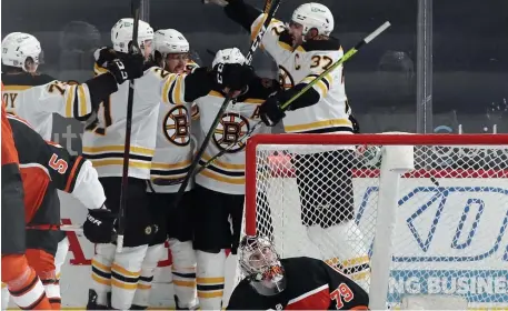  ?? Getty IMaGes Photos ?? HAT TRICK: Bruins players mob winger David Pastrnak after he scores the tying goal to force overtime against the Flyers on Wednesday night. Pastrnak assisted on Patrice Bergeron’s game-winning goal, left, in extra time as well, as the Bruins mounted yet another comeback victory.