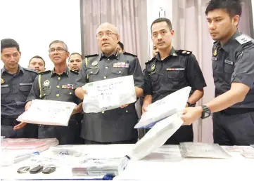  ??  ?? Domestic Trade, Cooperativ­es and Consumeris­m Ministry (KPDNKK) enforcemen­t unit director Datuk Mohd Roslan Mahayudin (centre) and his team showing the cash that was seized from MBI premises during the operations yesterday. A total of 98 bank accounts...