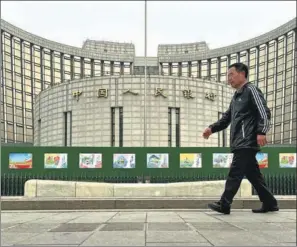  ?? JIANG QIMING / CHINA NEWS SERVICE ?? A pedestrian walks past the headquarte­rs of the PBOC in Beijing.