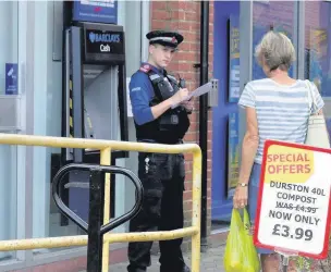  ?? TIM DODDS ?? A police officer at the Barclays ATM in The Square, Lightwater.